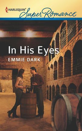 A couple standing next to a wooden wine barrel, sharing a bottle of wine, standing in a large wine cellar with brick walls. 